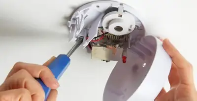 Certified technician wiring smoke detector during installation in Los Angeles, CA